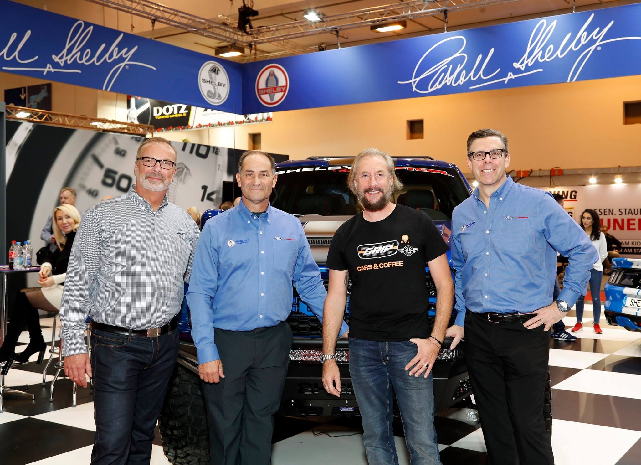 Four men posing at the GUA B.V. Shelby stand at Essen Motor Show